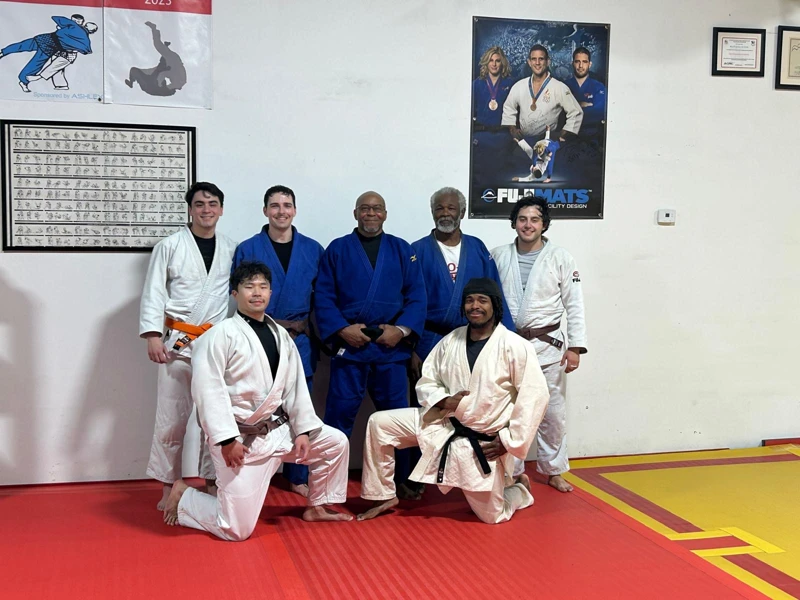 A group of men smiling at a judo club.